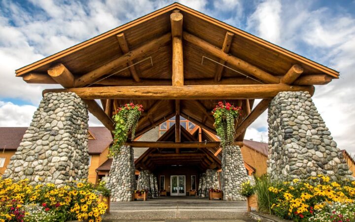 Exterior view of the front door with large stone pillars and A frame at Talkeetna Lodge in Alaska.