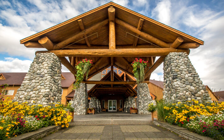 Exterior view of the front door with large stone pillars and A frame at Talkeetna Lodge in Alaska.