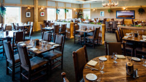 Several clean and set tables with plates and glasses at the Roraker Restaurant at Talkeetna Lodge in Alaska.