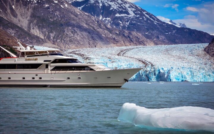 Golden Eagle yacht cruising in front of Glacier in southeast Alaska with icebergs around.