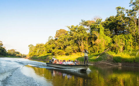 Small river boat filled with travelers and a guide exploring the upper amazon on a bright sunny day