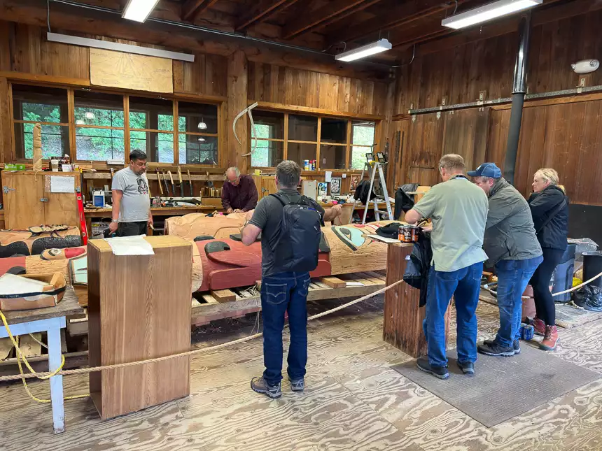 Group of travelers watches a live presentation on how traditional totem pole are made in Alaska. 