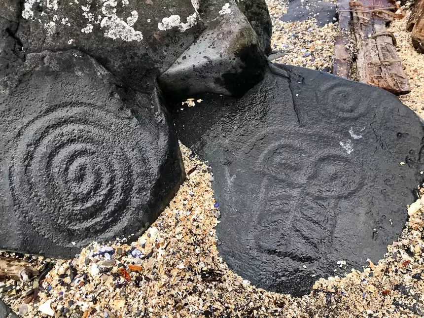 Petroglyph on a dark black rock in Wrangel, Alaska, seen among the sand on shore during an Alaskan dream cruise shore excursion.  
