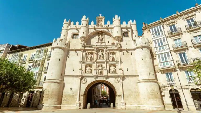 Santa maria arch in burgos that looks like a historic castle with small green trees on the ground on a sunny day