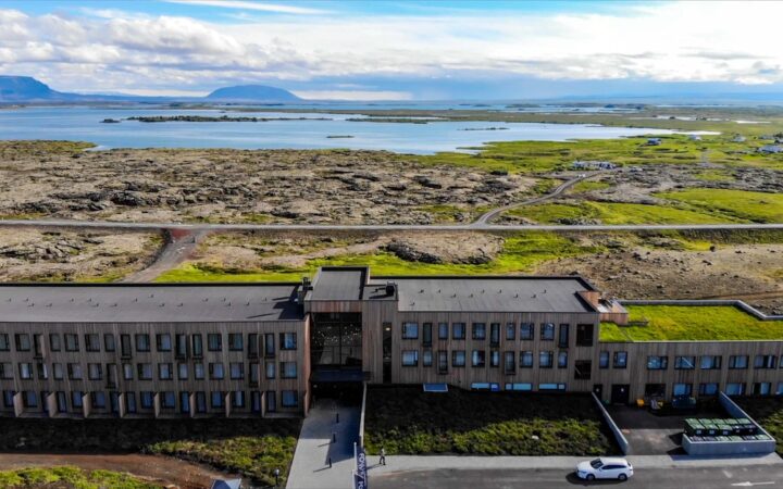 Aerial view of Fosshotel Myvatn Iceland hotel. A modern wood-paneled building sitting on a hillside overlooking the iconic lake.