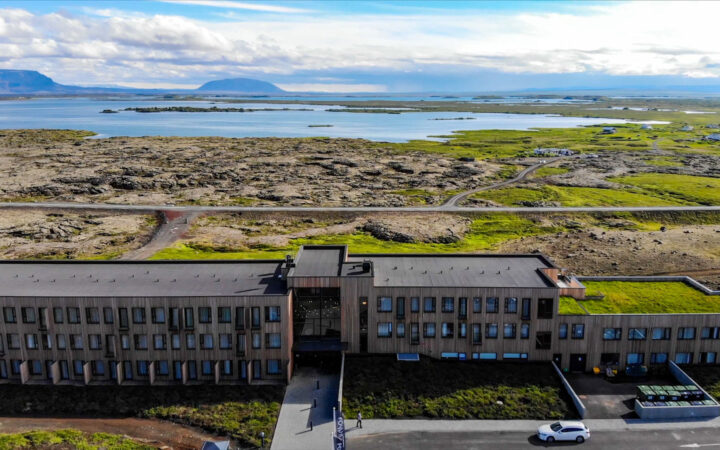 Aerial view of Fosshotel Myvatn Iceland hotel. A modern wood-paneled building sitting on a hillside overlooking the iconic lake.