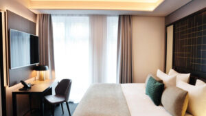 Suite bedroom at Hotel Reykjavik Saga with sky lights, double bed in white linens, desk & clean aesthetic.