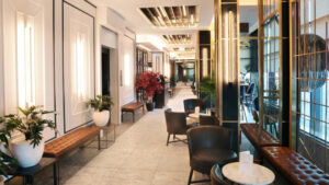 Bright hallway at Hotel Reykjavik Saga with tall windows, modern lighting, leather benches & chairs & small marble tables.