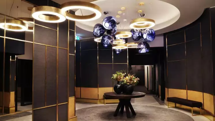 Hotel Reykjavik Saga lobby with art deco design, colorful flowers in a vase, glass, gold, dark walls & accent lighting.