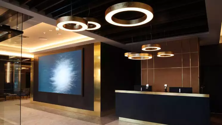 Hotel Reykjavik Saga reception desk with art deco design, modern artwork, gold, dark walls & accent lighting.