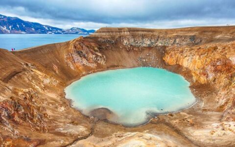 Aerial view of large tan volcanic crater with milky turquoise water in the center, seen on the Iceland Adventure: Land of Fire & Ice tour.