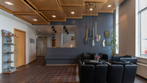 Lobby of Iceland Hotel Isafjordur, with wood floors, glass bookshelf with handicrafts, recessed lighting in cascading wood boxes, & black leather couches.