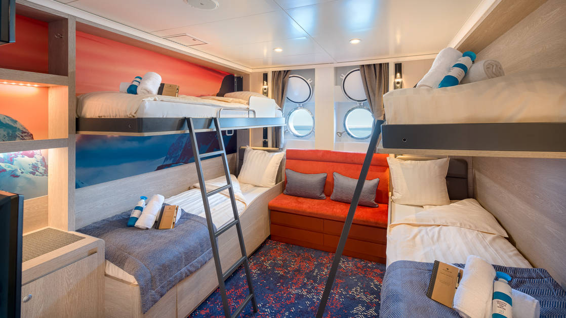 Hondius and Janssonius Quadruple Porthole stateroom with 4 berths, ladders, seating, desk, dresser and 2 small portholes.