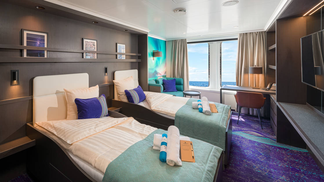 Hondius and Janssonius Twin Deluxe stateroom with twin beds, nightstand, desk and 2 large windows.