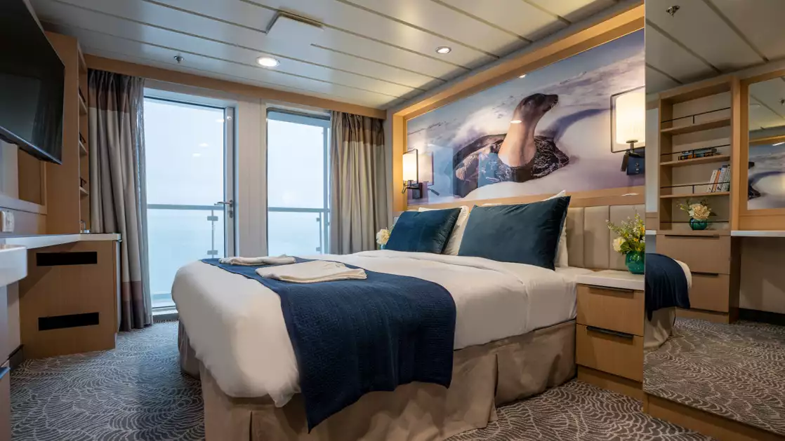 double bed aboard small ship cruise in antarctica with blue and white tones and floor to celling windows and balcony