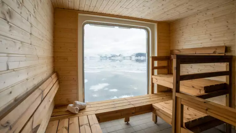Suana aboard small cruise ship with a large window to look out onto the ice
