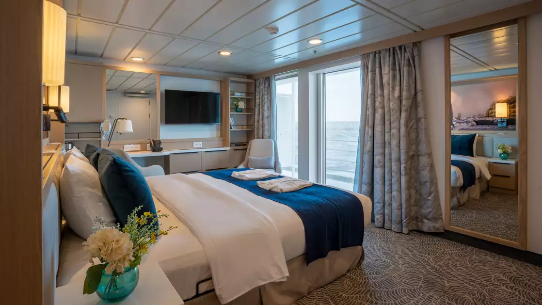 double bed aboard small ship cruise in antarctica with blue and white tones and balcony with seating