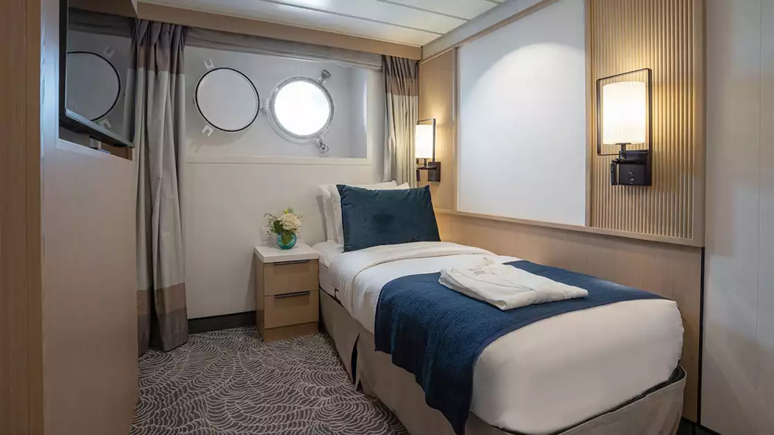 single suite aboard small ship cruise in antarctica with blue and white tones and a porthole window
