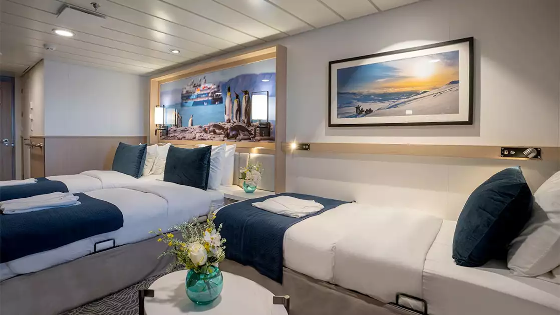 Triple bedroom aboard small ship cruise in antarctica with blue and white tones and floor to celling windows
