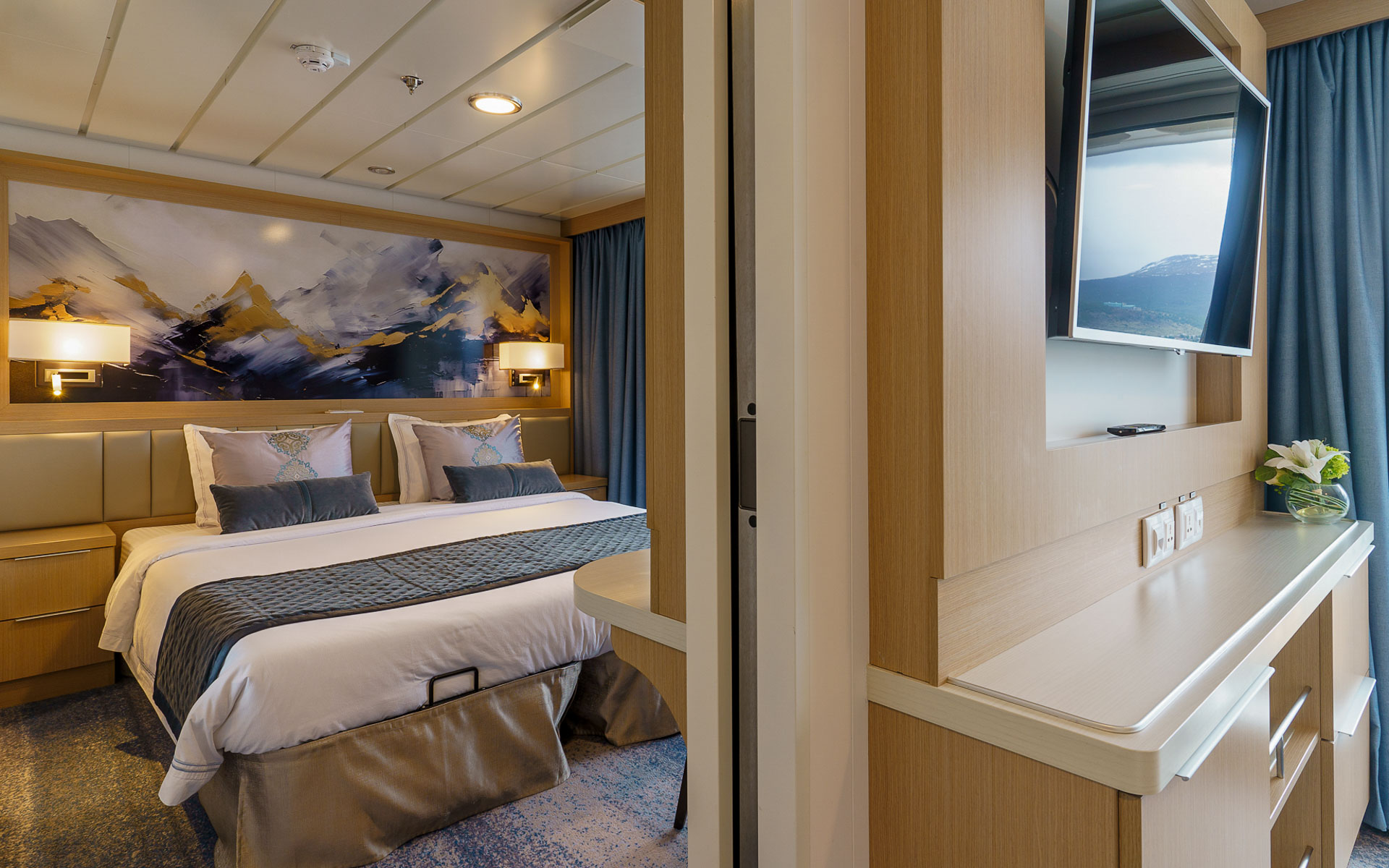 Penthouse Suite bedroom on Ocean Explorer with double bed in white sheets by floor-to-ceiling windows & big balcony.