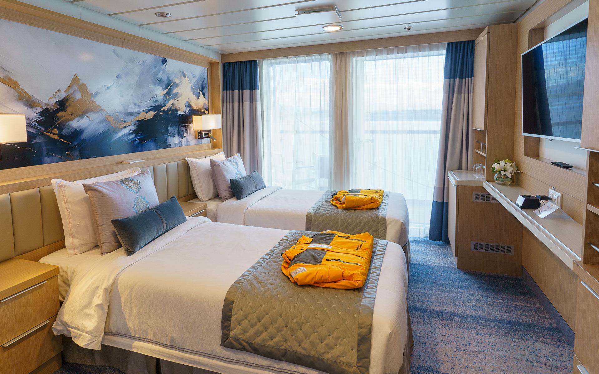 Veranda Stateroom on Ocean Explorer ship with twin beds in white sheets, desk, map headboard & balcony.