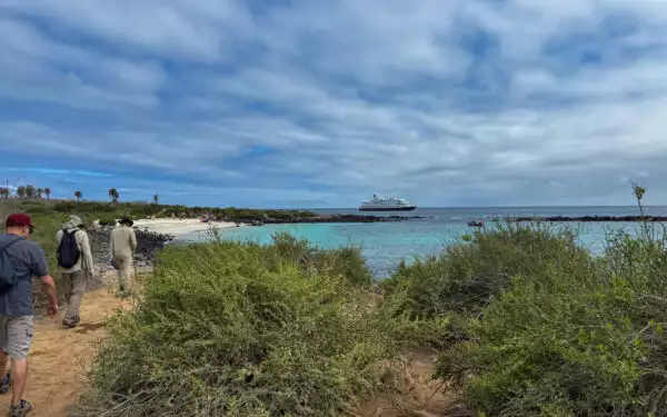 Hikers walking along the shore off their small cruise ship in the Galapagos on a bright sunny day