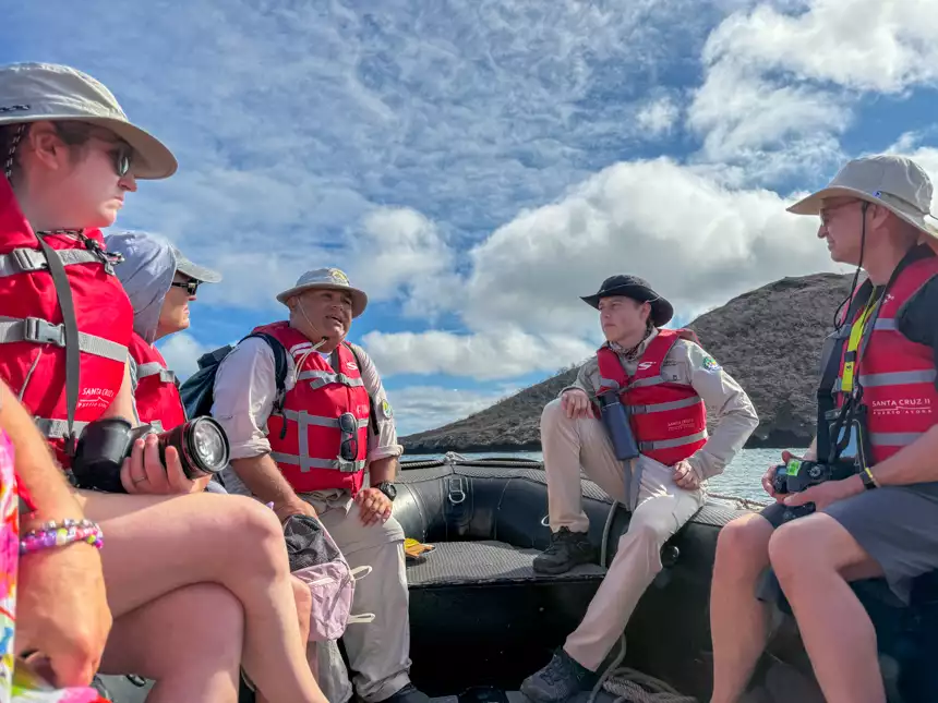 Guide informing guests on small ship zodiac through the Galapagos islands on a sunny cloudy day