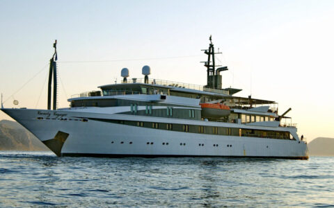 Small cruise ship with large windows on a calm evening with the sun setting