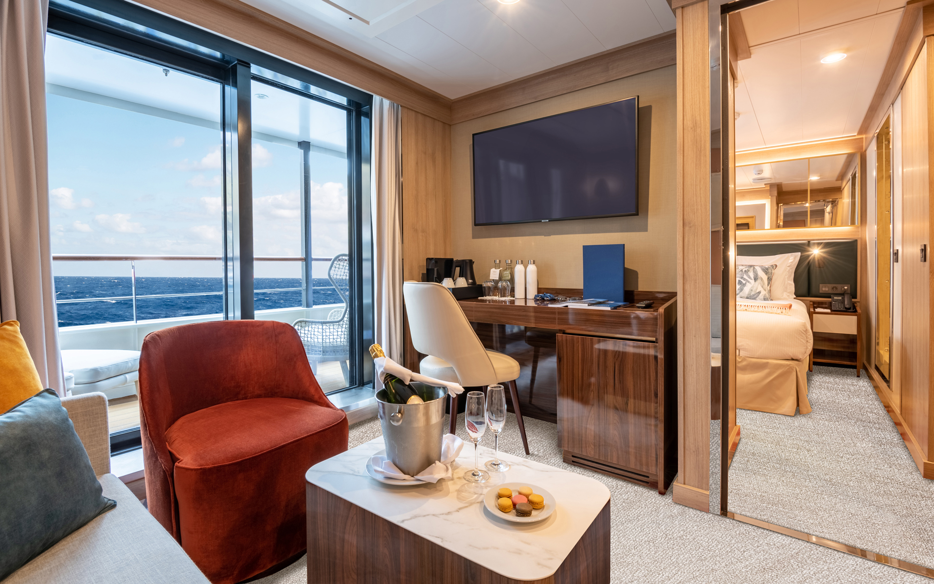 Owner's Suite on World Voyager cruise ship with large step-out balcony, separate sitting room with couch, desk & TV & bedroom.