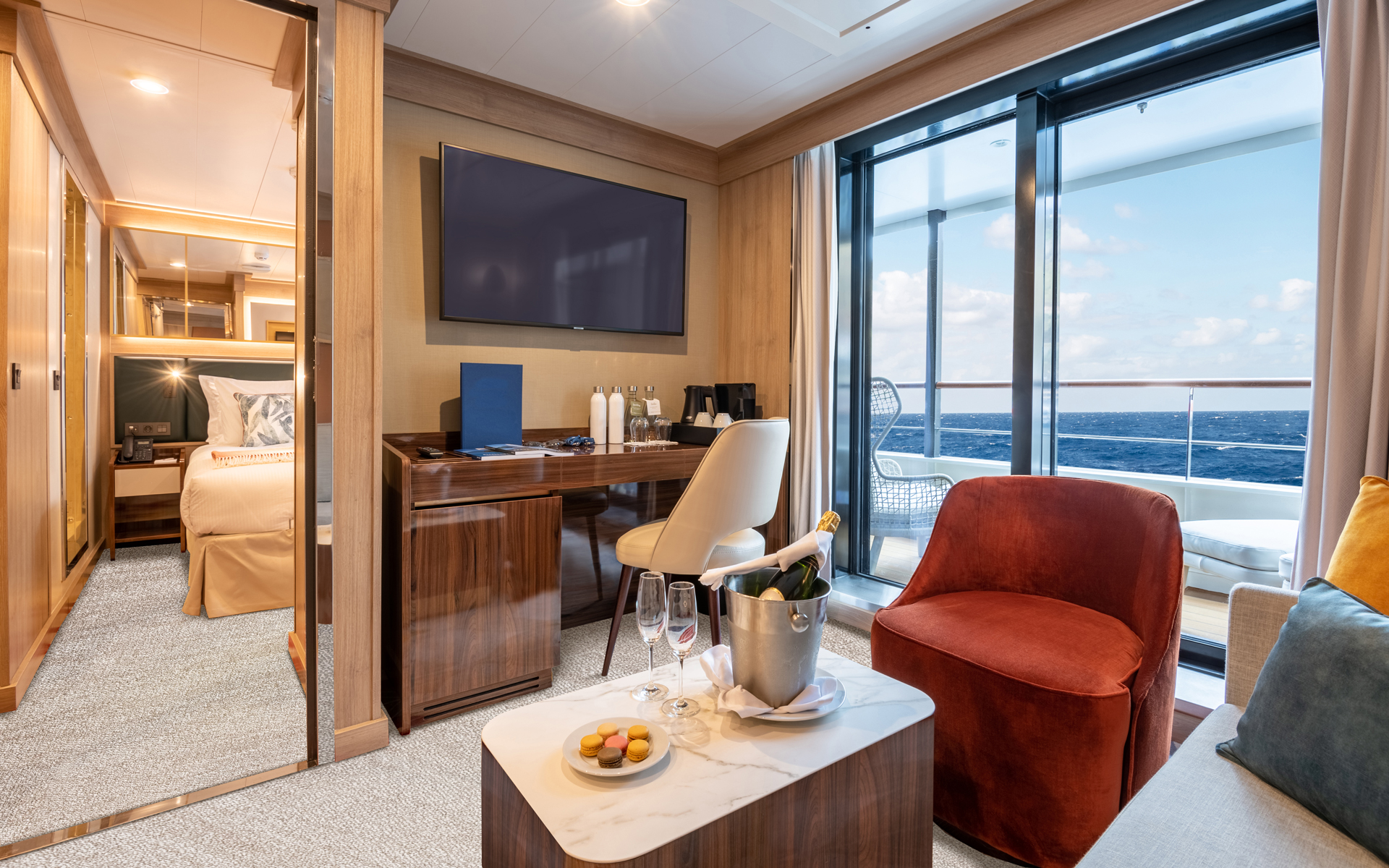 Superior Suite on World Voyager cruise ship with large step-out balcony, separate sitting room with couch, desk & TV & bedroom.
