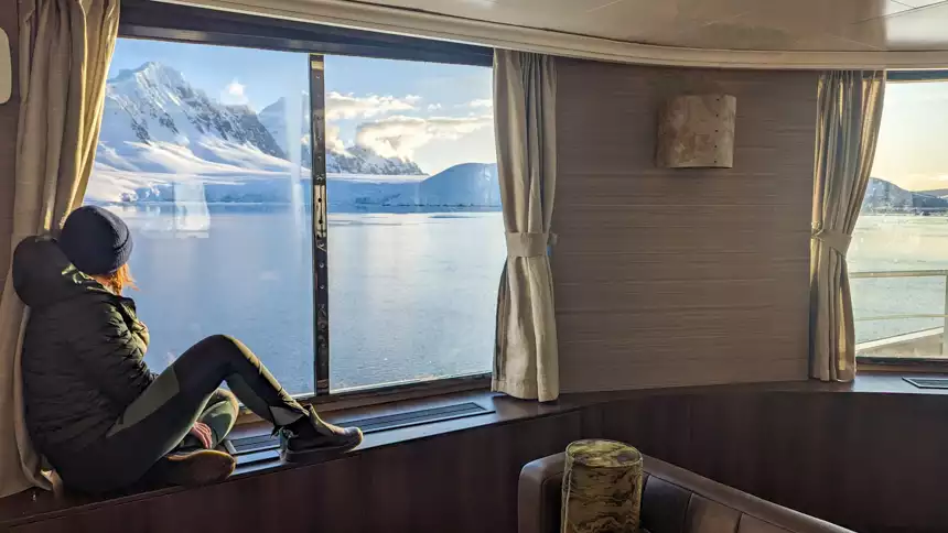 Women sitting in the window of small cruise ship Hondius as she looks out at the breathtaking mountains 