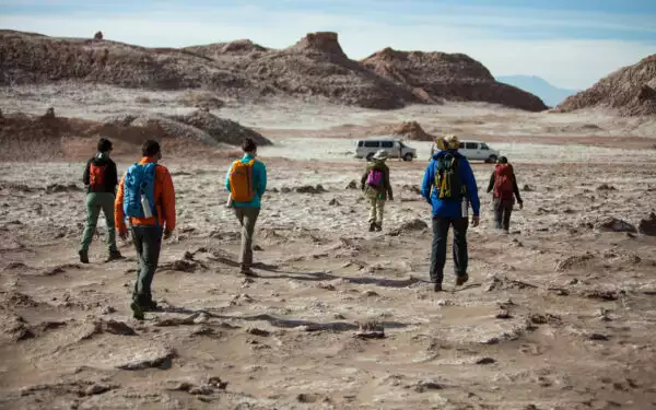 A small group of 6 travelers walks on Chile's Atacama desert during a guided tour