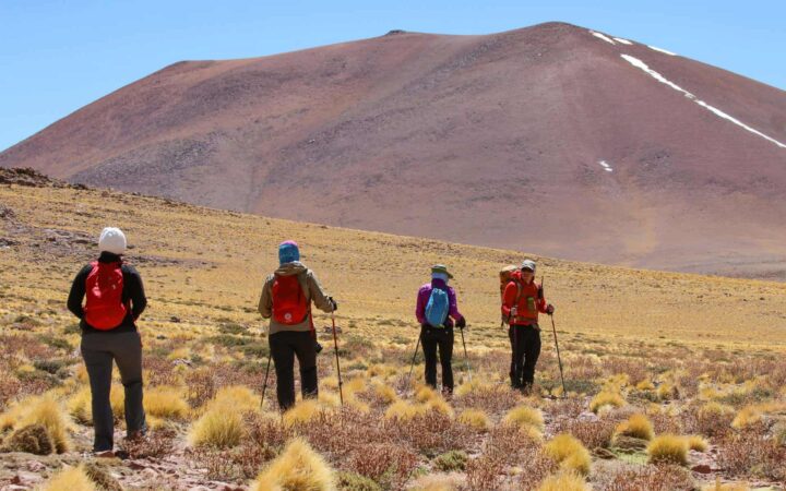 adventure travelers on a chile tour in Atacama trekking with mountains in the background.