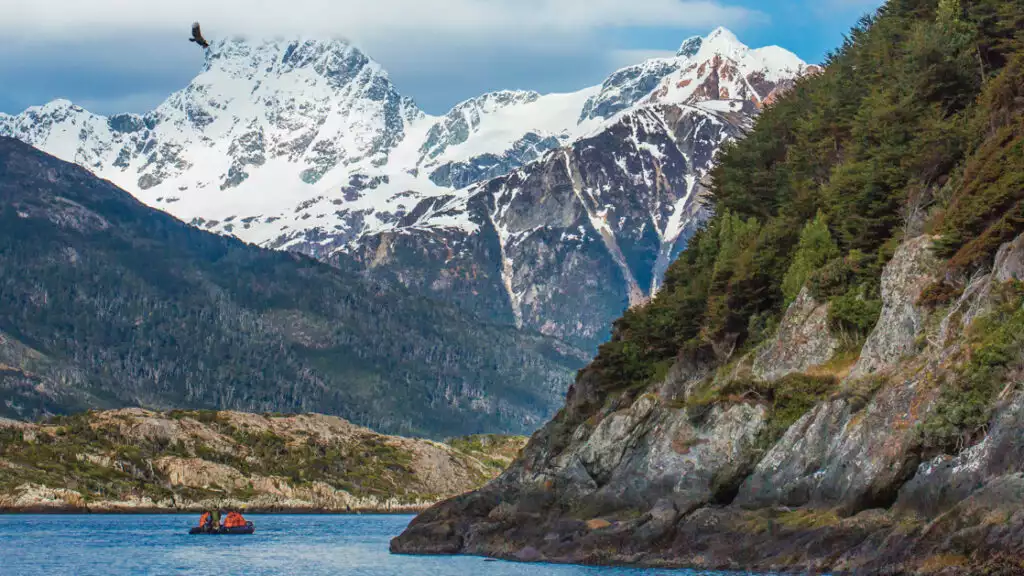 Guests explore by zodiac in Karukinka Natural Park, Chile next to snowy steep mountains