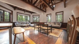 Minimalist common area at Explora Patagonia National Park Lodge with wood floors & seating, windows along each wall & wood beams.
