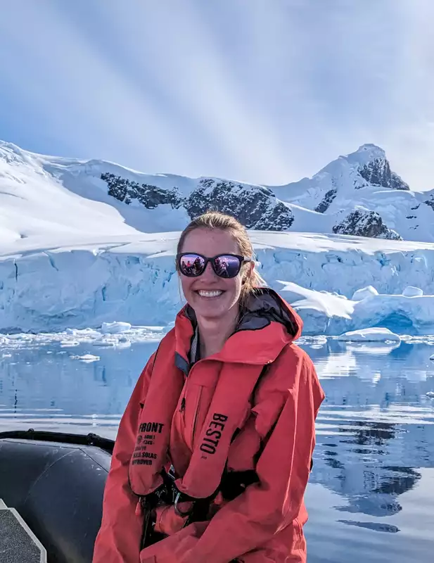 Adventure Specialist Lauren sitting on a zodiac in front of a gorgeous icy landscape 