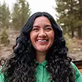 Adventuresmith explorations maya torres pictured outside on a winter day with bright green jacket on