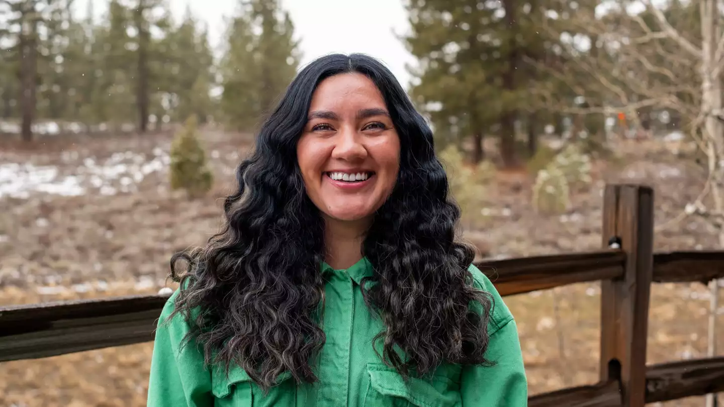 Adventuresmith explorations maya torres pictured outside on a winter day with bright green jacket on