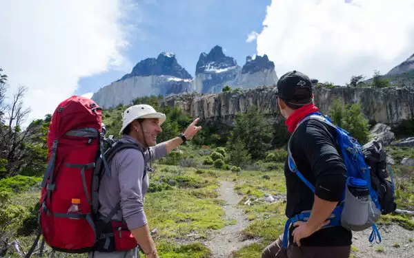 A guide points out iconic Patagonia peaks to a male traveler who looks up at the mountains