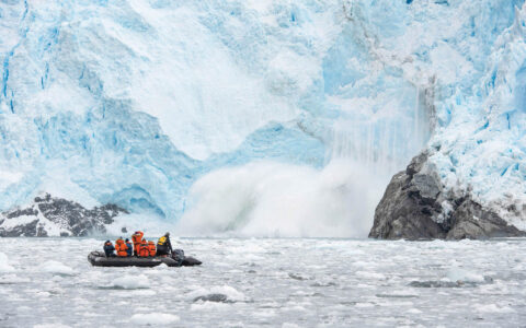 Guests witness a dramatic ice calving event in Seno Hyatt fjord, deep in the remote wilderness of Tierra del Fuego, Patagonia, Argentina.