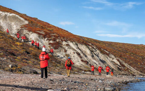 Hikers dressed in red jackets explore hilly beach with red landscaped