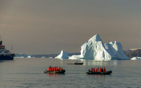 two zodiacs filled with travelers explore icebergs off a small cruise ship