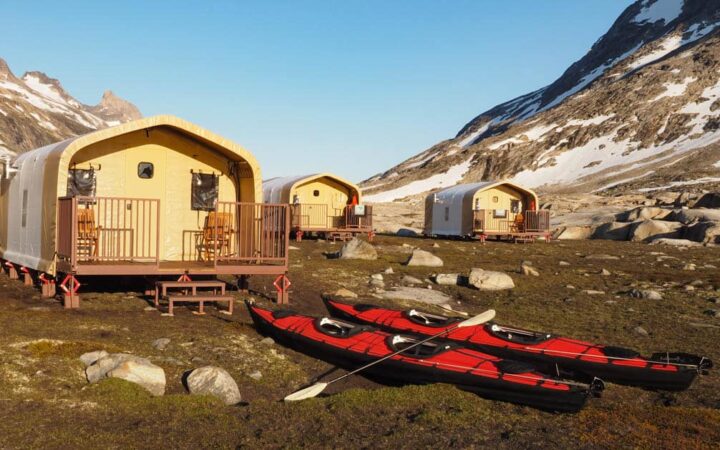 Safari-style tent cabins with two kayaks out front at Base Camp Greenland, in Sermilik Fjord