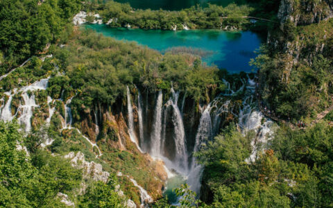 Cascading waterfalls among the trees at Plitvice Lakes seen from above with a footpath barely visible to the right