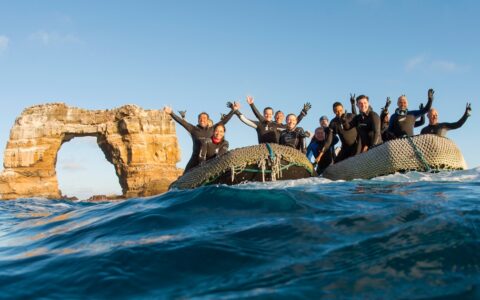 Scuba divers from the Galapagos Sky pose next to Darwins's Arch offshore Darwin Island on a sunny day in Galapagos, Ecuador.