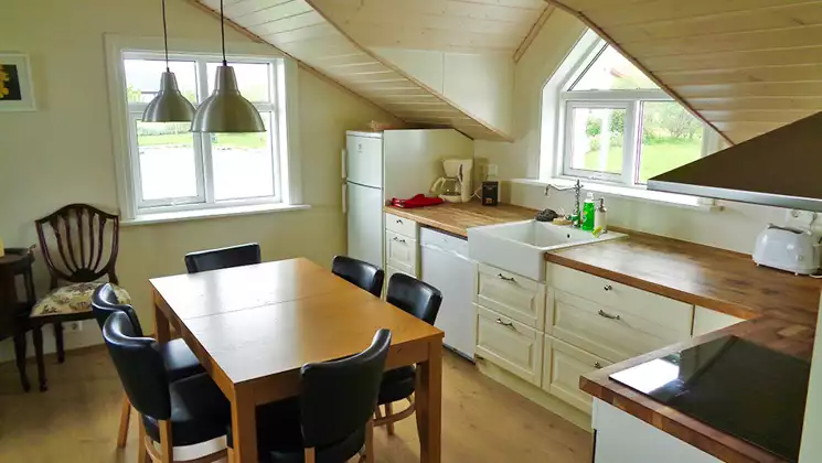 Kitchen in a small cabin at Hali Country Hotel in Iceland with wood table & countertop, induction stove & dormer windows.