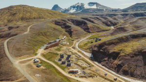 Aerial view of Highland Base Hotel in Iceland with dirt roads leading into a riverside canyon with various small buildings.