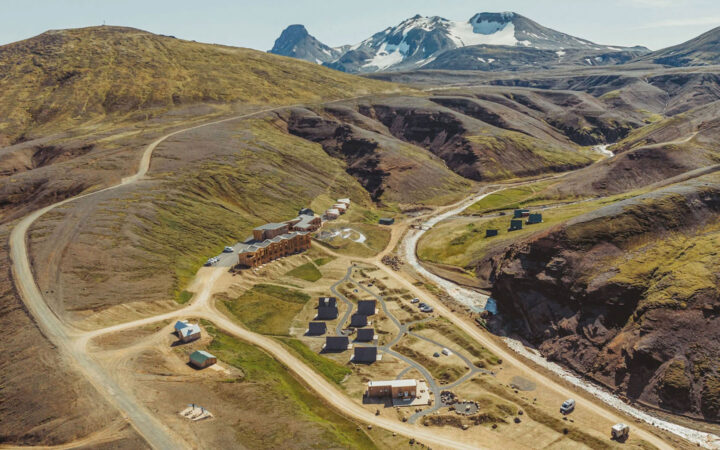 Aerial view of Highland Base Hotel in Iceland with dirt roads leading into a riverside canyon with various small buildings.