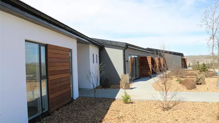 Exterior of northeast Iceland's Hotel 1001 Nott, with stone gardens, private guestroom patios, wood & white walls.