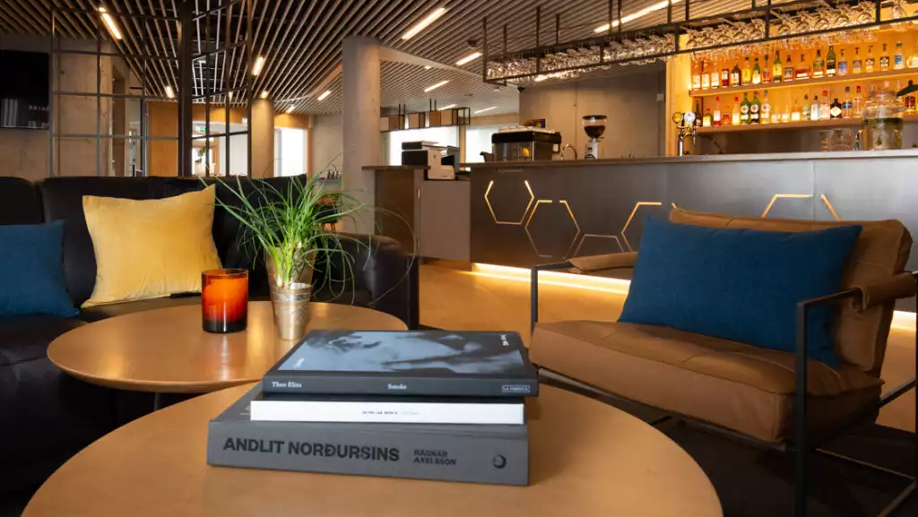 Lounge & bar at Landhotel in South Iceland with modern aesthetic of steel & wood, with stuffed chairs of leather, blue & gold.